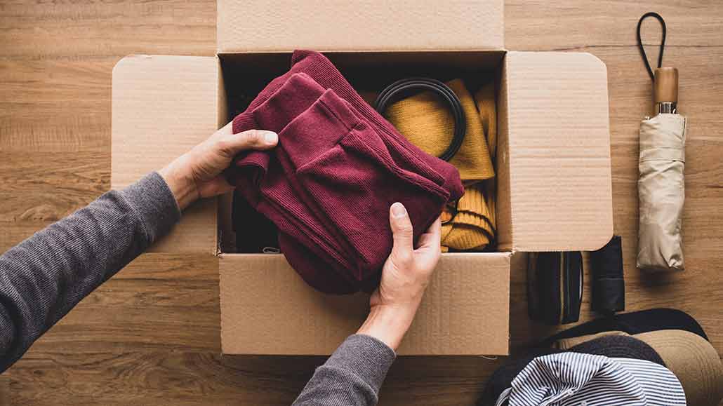 A person holding a folded sweater in a box