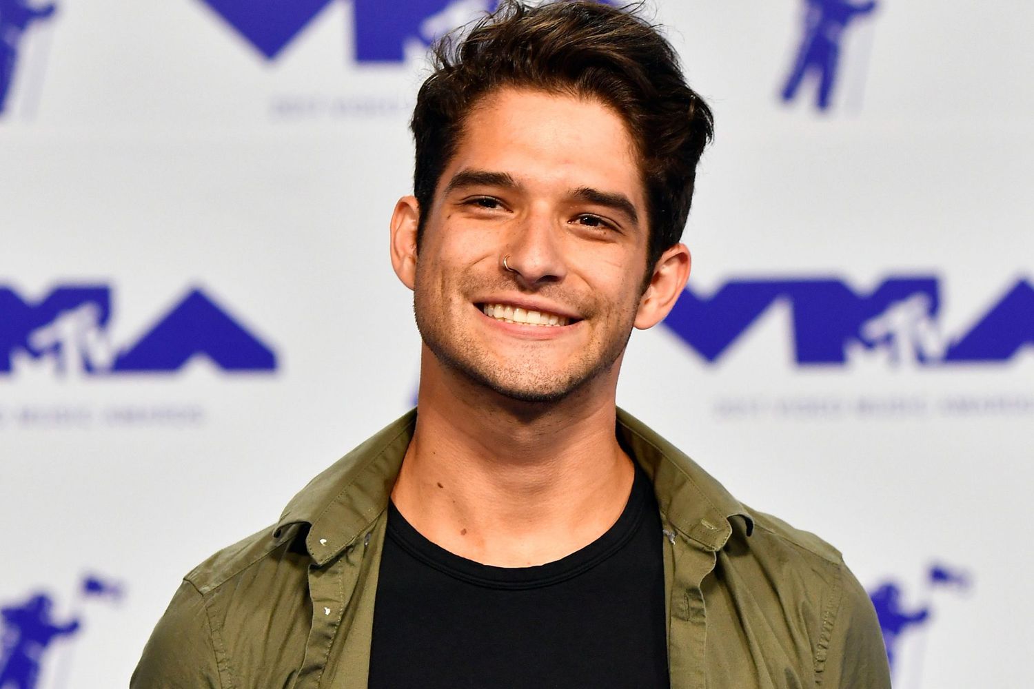 Tyler Posey wearing shirt with a big smile at an event