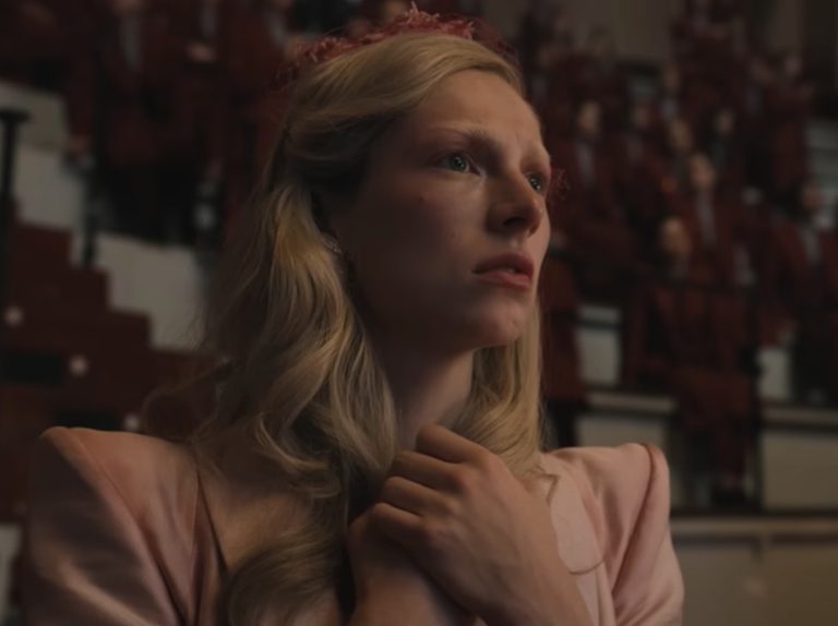 Hunter Schafer wears a pink suit and a crown as she plays Tigris Snow
