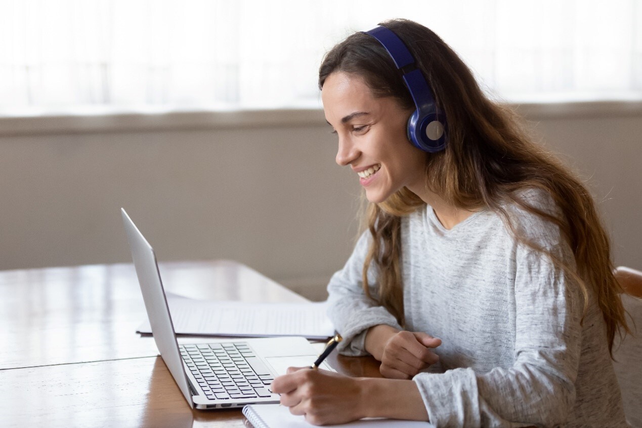 A woman using a blue wireless headset with a laptop
