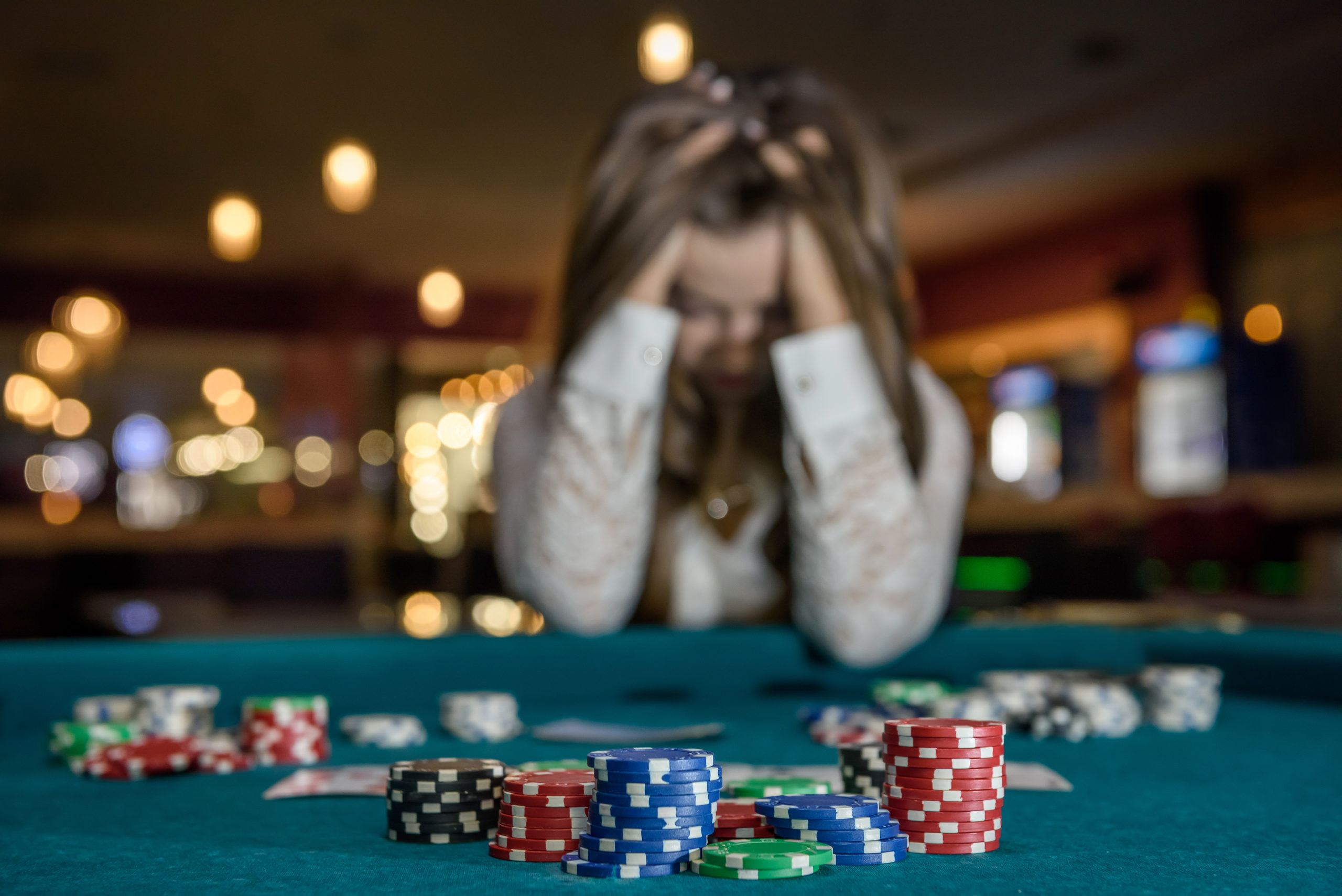 An upset woman in a casino sitting behind a poker table