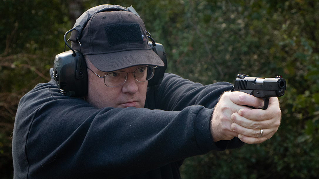 A man in black jacket holding a pistol