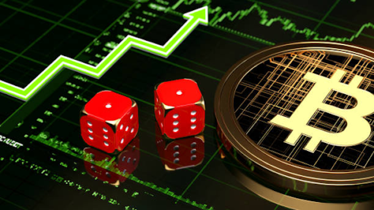 A pair of dice rest on top of a Bitcoin, positioned in front of a financial graph